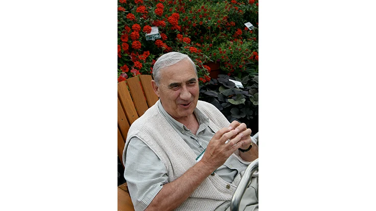 Man sitting in chair in front of green shrub