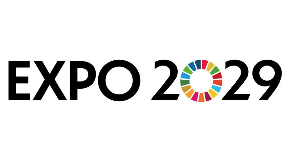 A logo says Expo 2029 in black capital letters on a white background. The 0 in 2029 is made up of multicolored wedges.