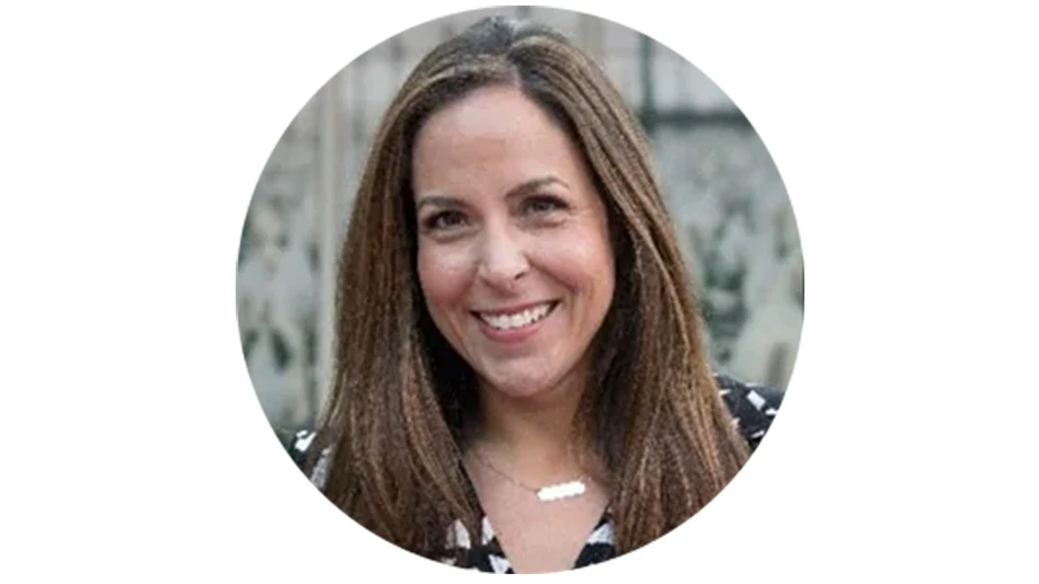 A woman with long brown hair smiles at the camera.
