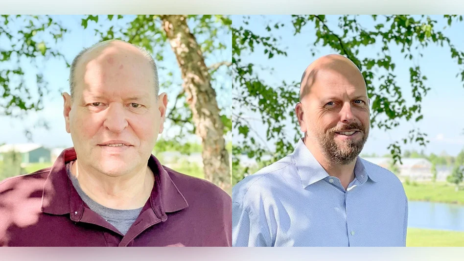 Two men posing in front of trees outside.
