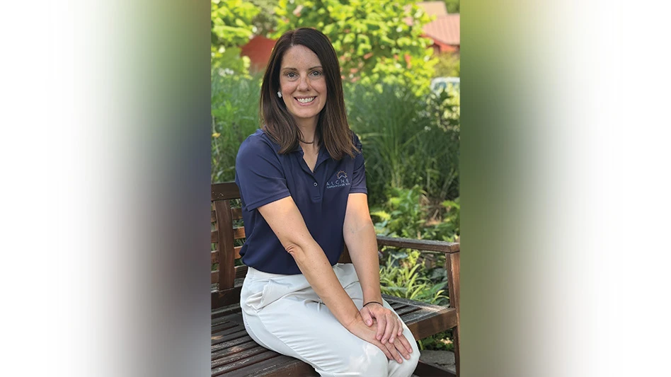 A photo of a smiling woman sitting on a bench.