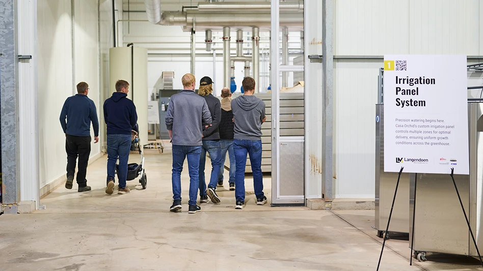 Six people walk into a high-tech greenhouse area.