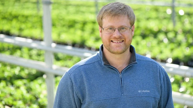 Man posing in front of green fields